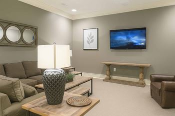 A living room with a brown couch, a wooden coffee table, and a flat screen TV mounted on the wall.